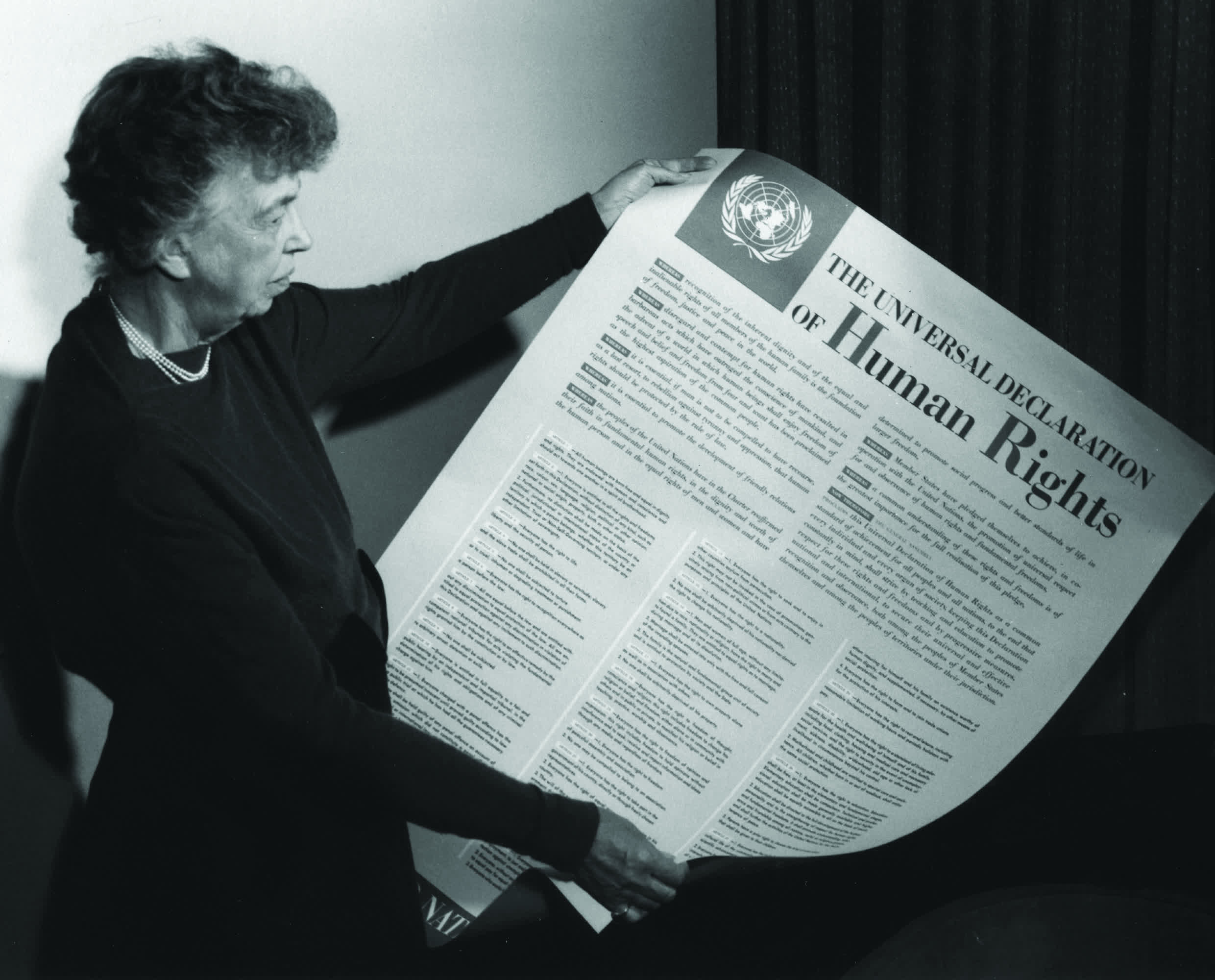 Woman holding the full Universal Declaration of Human Rights document printed in large format.